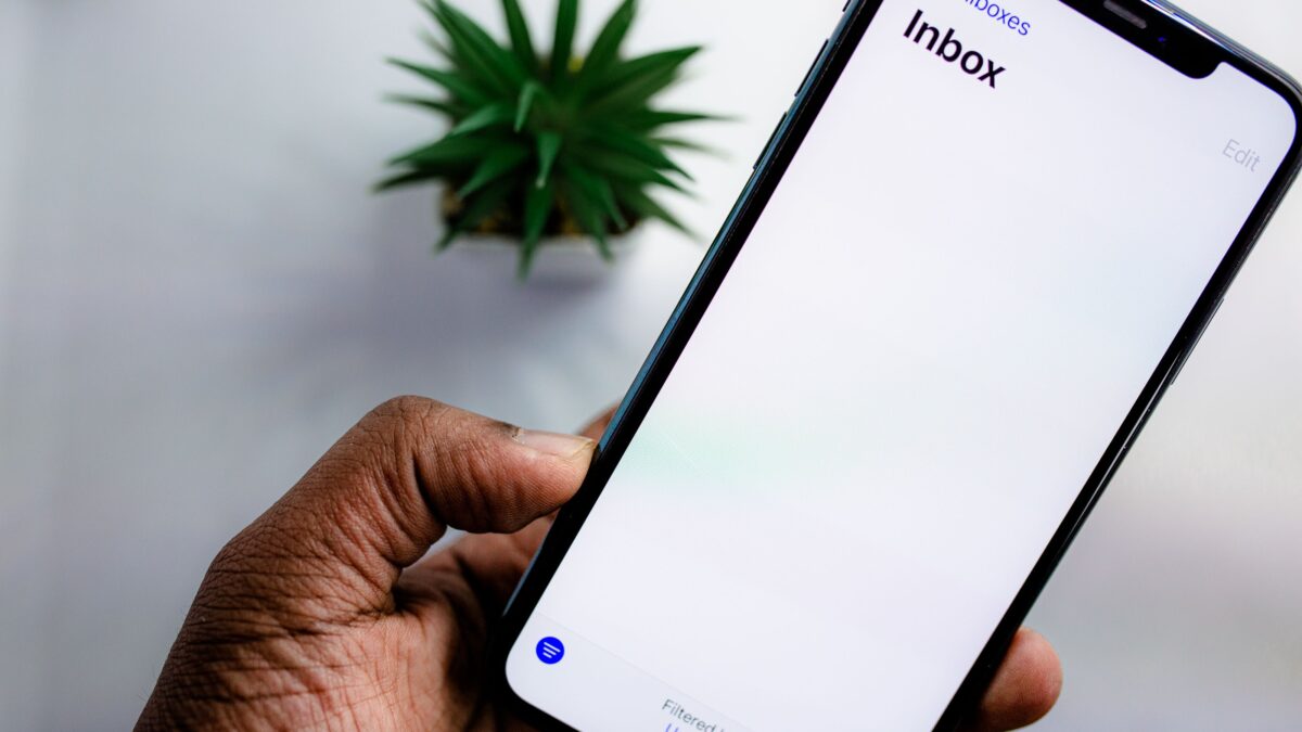 Persoon bekijkt e-mailinbox op smartphone, symbool voor waakzaamheid tegen phishingmails na een datalek