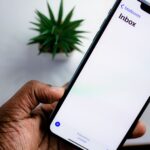 Persoon bekijkt e-mailinbox op smartphone, symbool voor waakzaamheid tegen phishingmails na een datalek
