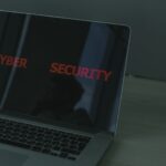 Laptop met de rode tekst CYBER SECURITY op het scherm, symbool voor phishing via gehackte websites